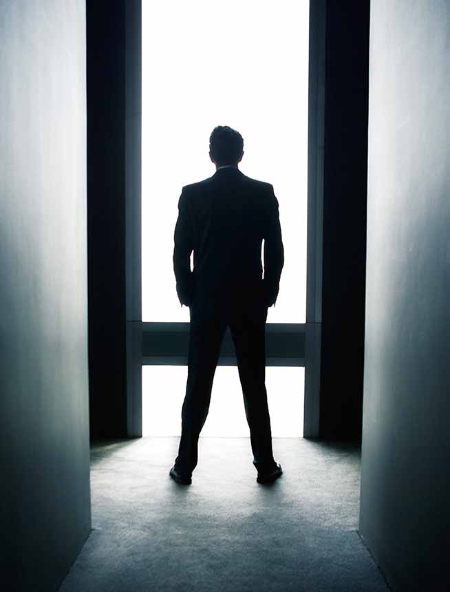 Silhouette of man looking out of window