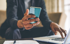 man with laptop holding a phone