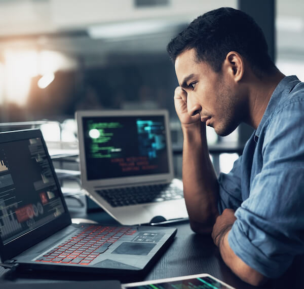 Frustrated man on computer on true cost of fraud